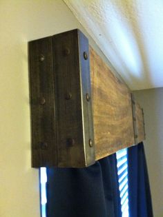 an old wooden box hanging from the side of a window with blue curtains behind it