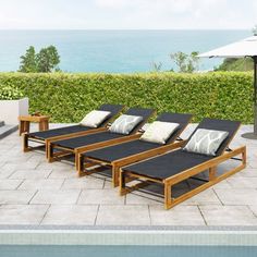 three lounge chairs sitting next to each other in front of a pool with an ocean view