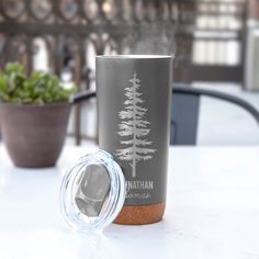 a stainless steel tumbler next to a potted plant