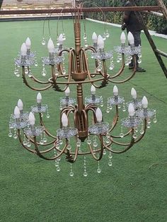 a chandelier hanging from a wooden pole in the middle of a grassy area