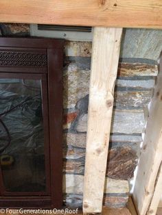 a fire place sitting in the corner of a room next to a wall with logs on it