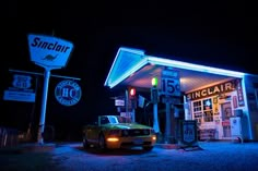 a car parked in front of a gas station at night with neon lights on it