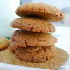 a stack of cookies sitting on top of a wooden plate next to a glass of milk