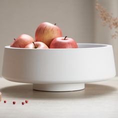 some apples are in a white bowl on a table