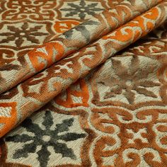 an orange and brown patterned fabric with black, white, and grey designs on it