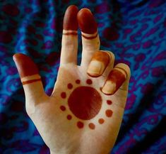 a person's hand with red and white designs on it holding up their palm