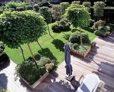 an aerial view of a garden with trees and lawn furniture in the foreground, surrounded by wooden decking