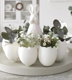 some white eggs with flowers and an egg shaped like a bunny sitting on top of them