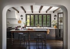 an archway leading into a kitchen with two stools and a table in the middle