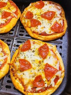 four pepperoni pizzas sitting on top of a black grill grate with cheese and seasoning