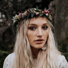 a woman with long blonde hair wearing a flower crown on her head and looking at the camera