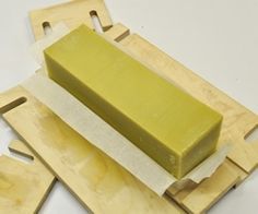 a green block of soap sitting on top of a wooden cutting board next to two pieces of wood