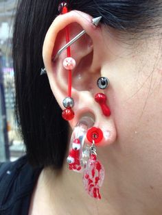 a woman wearing red and silver ear piercings