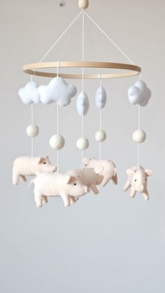 a baby mobile with sheep and clouds hanging from it's sides in a room