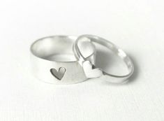 two silver rings with hearts on them sitting next to each other in front of a white background