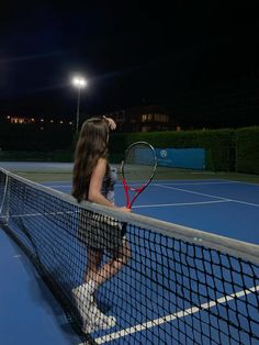 a woman standing on a tennis court holding a racquet in her hand and looking at the sky