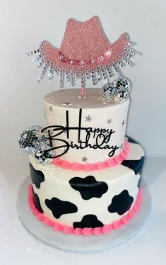 a birthday cake decorated with cow print and pink frosting, has a happy birthday sign on top