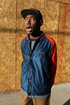 a man standing in front of a wooden wall with his mouth open and tongue out