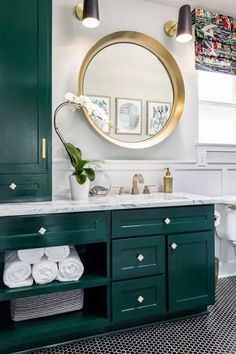 a bathroom with green cabinetry and white walls, black and white tile flooring