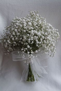 a bouquet of white baby's breath flowers on a white cloth covered tablecloth