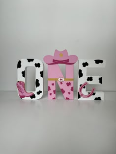 the word one is decorated with pink and black polka dots, cowboy boots, and a cow print