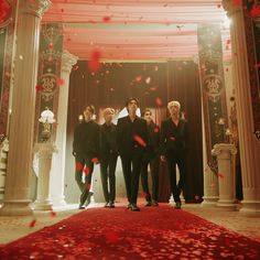 a group of people standing on top of a red carpet in front of an archway