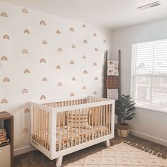 a baby's room with a white crib and rainbow wall decals on the walls