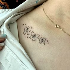 a woman's chest with three butterflies tattoo on her left side ribcage