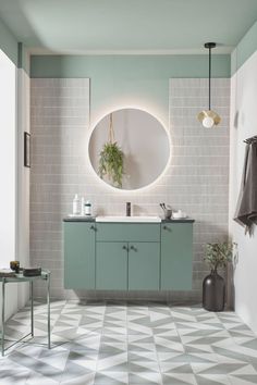 a bathroom with a sink, mirror and tiled flooring in pastel green tones