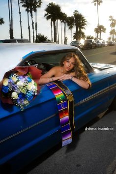 a woman sitting in the back of a blue car with a bouquet of flowers on it