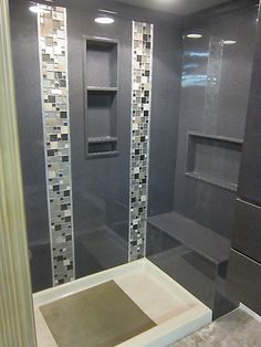 a walk in shower sitting next to a tiled wall and floor covered in gray tiles