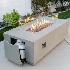 a fire pit sitting on top of a white tile floor next to a lush green yard