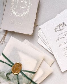 the wedding stationery is laid out on top of each other, including two envelopes and a wax seal