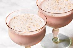 two glasses filled with pink liquid sitting on top of a white counter next to each other