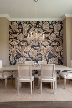 A dining room with a bold floral wallpaper accent wall and a chandelier. A N Wallpaper, Wallpaper Accent, Wallpaper Accent Wall