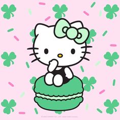 a hello kitty sitting on top of a cupcake with shamrocks around her neck