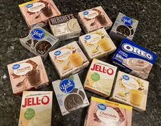 six boxes of jello are on the counter next to some chocolates and milk