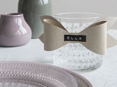 a glass vase with a bow on the front and label that says ella next to it