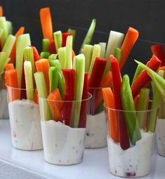 small cups filled with different types of veggies on top of a white table