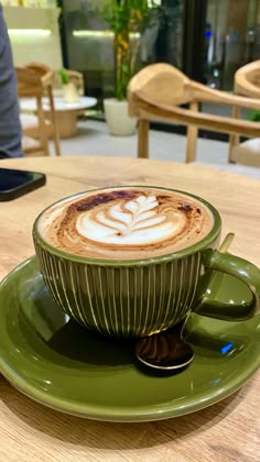 cappuccino in green saucer on wooden table