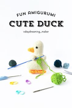 a crocheted duck sitting on top of a table next to yarn and knitting needles