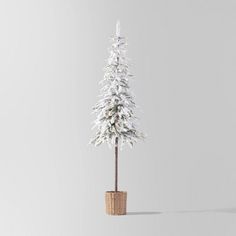 a small white christmas tree in a wicker basket with snow on the top and bottom