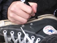 a person holding a pair of scissors in their hand while sitting on a black shoe