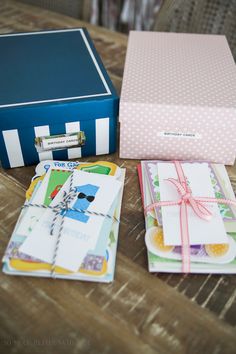 some cards are sitting on a table next to a blue box with a pink bow