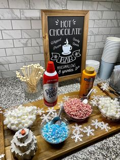 a table topped with lots of different types of cakes and cupcakes next to a sign