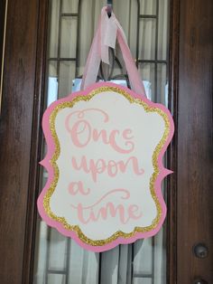 a pink and gold door hanger that says once upon a time