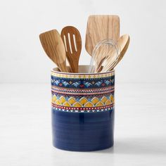 wooden utensils and spoons in a blue ceramic container with colorful designs on it