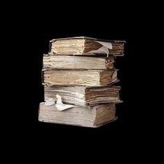 a stack of old books sitting on top of each other in front of a black background