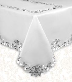 a white table cloth with silver trimmings and flowers on the edge is shown