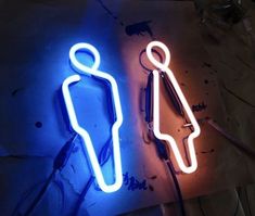 two neon signs that are sitting on top of a table next to scissors and pens